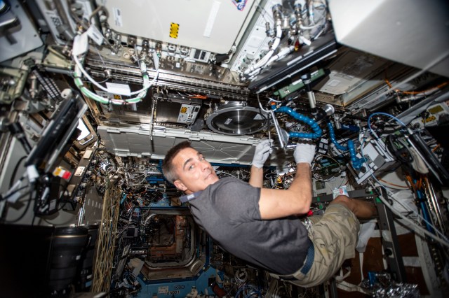 NASA astronaut and Expedition 63 Commander Chris Cassidy works in the Combustion Integrated Rack, connecting water umbilicals and checking for leaks in the research device that enables safe fuel, flame and soot studies in microgravity.