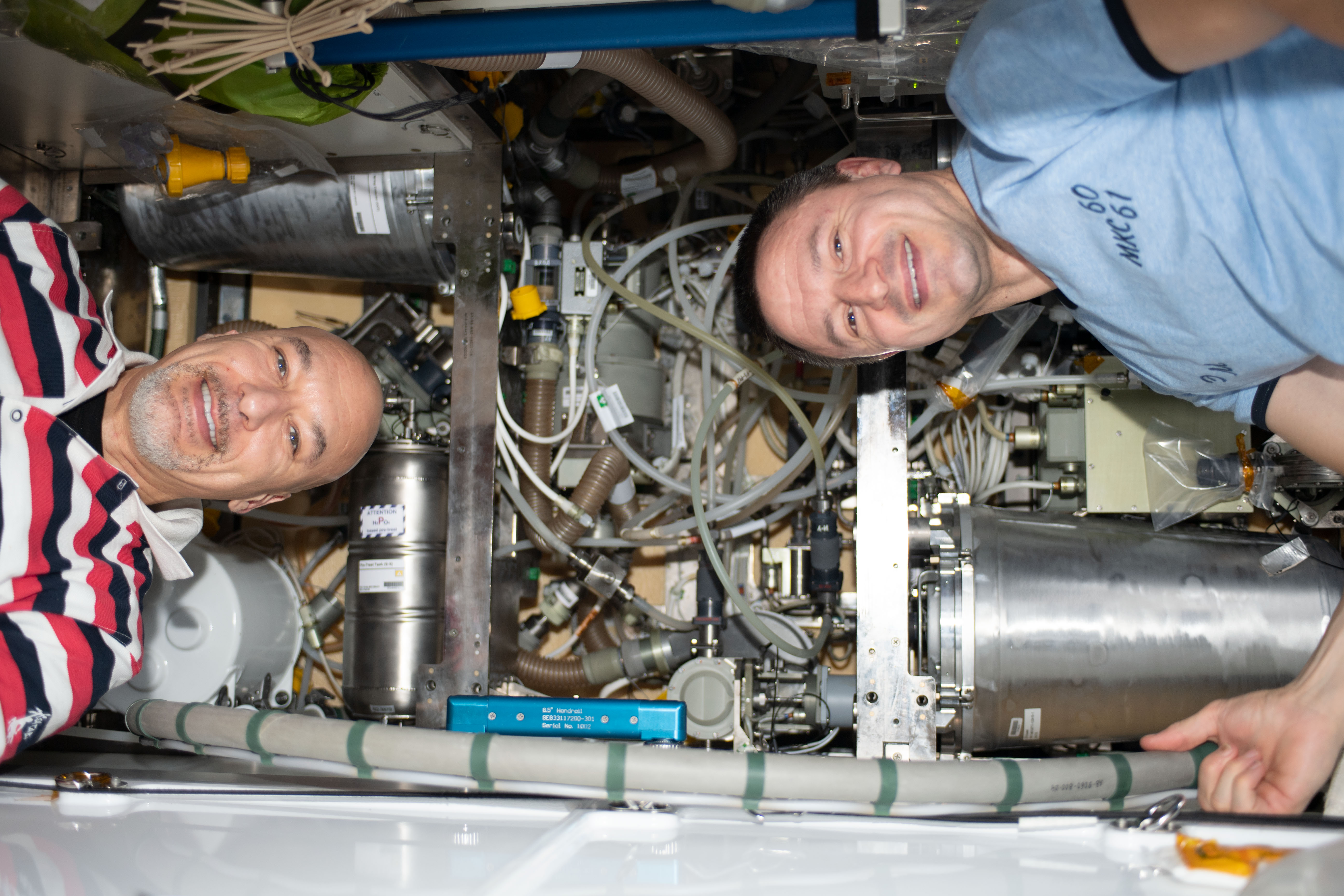 From left, Expedition 61 Commander Luca Parmitano of ESA (European Space Agency) and NASA Flight Engineer Andrew Morgan are pictured replacing components inside the International Space Station's bathroom, the Waste and Hygiene Compartment.