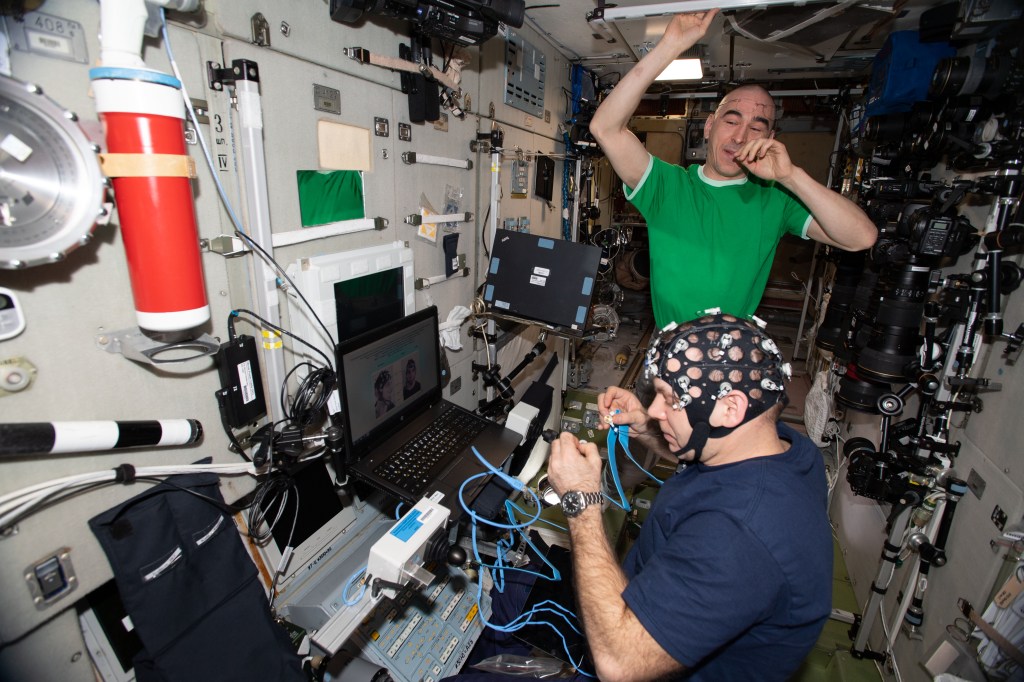 Roscosmos cosmonauts and Expedition 63 Flight Engineers Ivan Vagner (foreground) and Anatoly Ivanishin are pictured inside the International Space Station's Zvezda service module. Vagner is wearing Neurolab hardware for the Russian Pilot-T experiment that explores how space travelers may pilot future spacecraft on planetary missions.