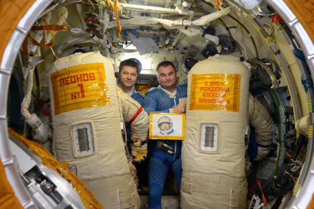 Cosmonauts Oleg Kononenko (left) and Alexey Ovchinin commemorated Alexei Leonov, the first human to walk in space, who turns 85 on Thursday, with signs attached to their Orlan spacesuits during their May 29, 2019, spacewalk. The sign attached to the spacesuit at left translates to, "Leonov #1." The sign on the spacesuit at right says, “Happy Birthday, Alexei Arkhipovich,” (Leonov’s patronymic name).
