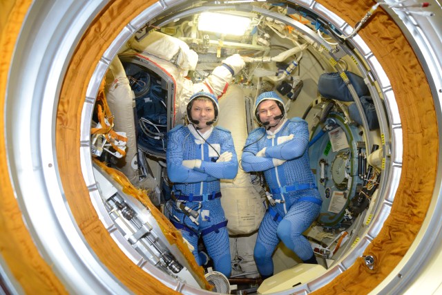 Cosmonauts Oleg Kononenko (left) and Alexey Ovchinin prepare their Russian Orlan spacesuits in the Pirs docking compartment's airlock ahead of a spacewalk that took place May 29, 2019.