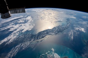 The International Space Station orbits 255 miles above the Atlantic Ocean looking southwest over Cuba as the Sun's glint beams off the Caribbean Sea.