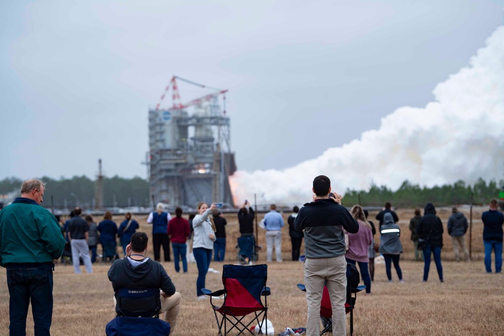 employees gather at the viewing site to witness the RS-25 test conducted on Jan. 23; Vapor clouds are seen in the background rising towards the sky.