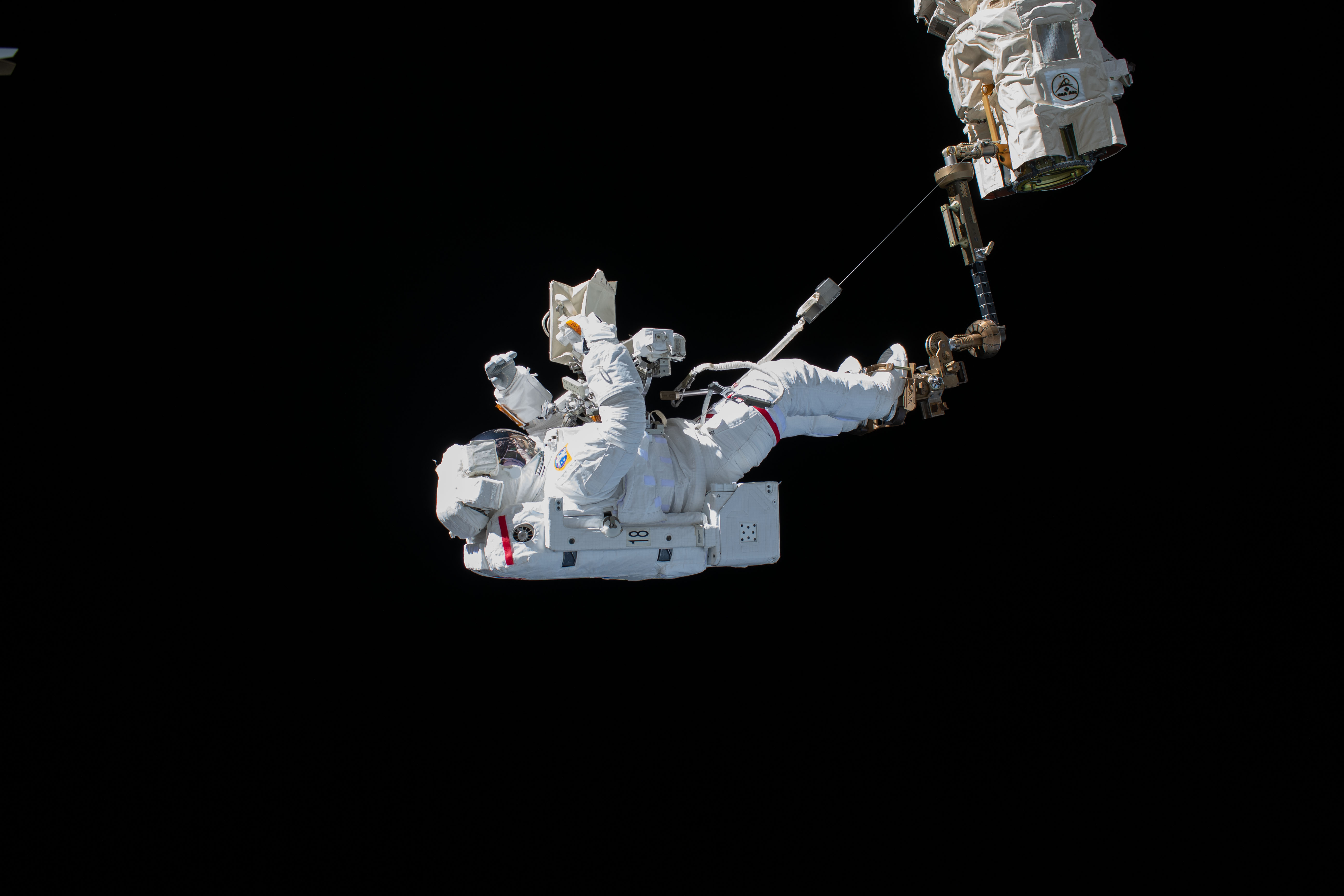ESA (European Space Agency) astronaut Luca Parmitano is pictured attached to the Canadarm2 robotic arm during the first spacewalk to repair the Alpha Magnetic Spectrometer, the International Space Station's cosmic particle detector.