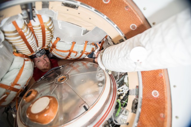 Expedition 57 Commander Alexander Gerst from ESA (European Space Agency) looks out from inside the Soyuz MS-09 spacecraft docked to the Rassvet module seemingly dwarfed by cargo bags and the Soyuz hatch.