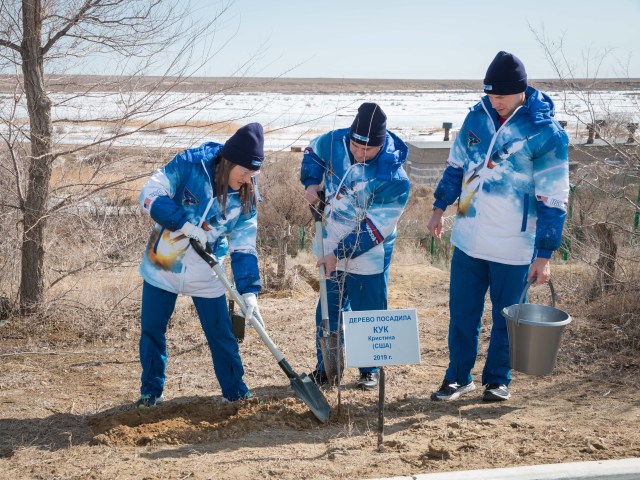 At the Cosmonaut Hotel crew quarters in Baikonur, Kazakhstan, Expedition 59 crew member Christina Koch of NASA (left) plants a tree in her name March 7 in traditional pre-launch activities. Assisting her are crewmates Alexey Ovchinin of Roscosmos (center) and Nick Hague of NASA (right). They will launch March 14, U.S. time, on the Soyuz MS-12 spacecraft from the Baikonur Cosmodrome for a six-and-a-half month mission on the International Space Station.