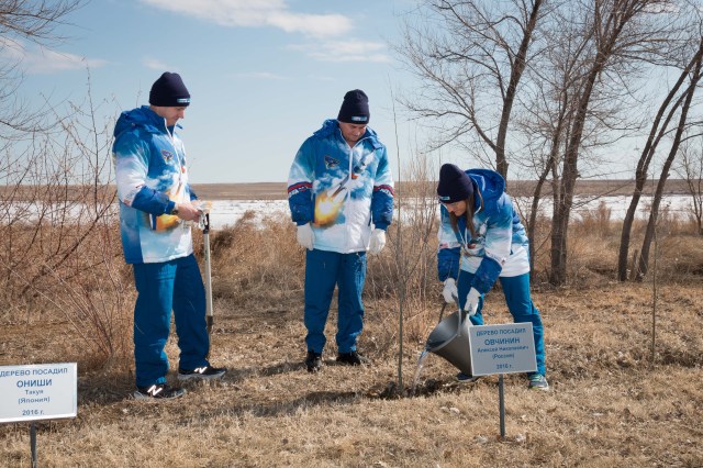 At the Cosmonaut Hotel crew quarters in Baikonur, Kazakhstan, Expedition 59 crew member Christina Koch of NASA (right) waters a tree March 7 originally planted last October by crewmate Alexey Ovchinin (center). Ovchinin and crewmate Nick Hague of NASA (left) launched together last October 11, but their flight was cut short two minutes after launch by an abort triggered by a first-stage booster rocket separation problem. They are set to launch again March 14, U.S. time, this time with Koch on the Soyuz MS-12 spacecraft from the Baikonur Cosmodrome for a six-and-a-half month mission on the International Space Station.