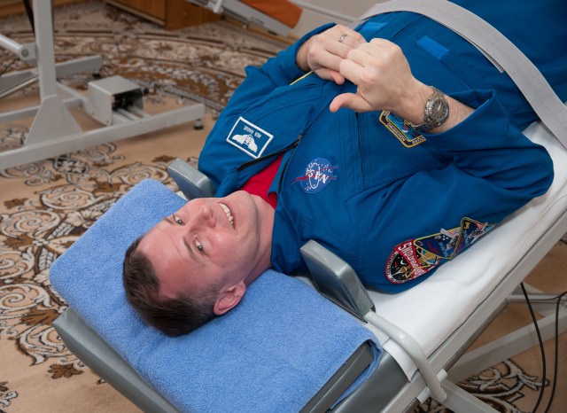 At the Cosmonaut Hotel crew quarters in Baikonur, Kazakhstan, Expedition 59 crew member Nick Hague of NASA flashes a thumbs-up signal as he tests his vestibular system on a tilt table March 7 as part of his pre-launch activities. Hague, Christina Koch of NASA and Alexey Ovchinin of Roscosmos will launch March 14, U.S. time, on the Soyuz MS-12 spacecraft from the Baikonur Cosmodrome for a six-and-a-half month mission on the International Space Station.