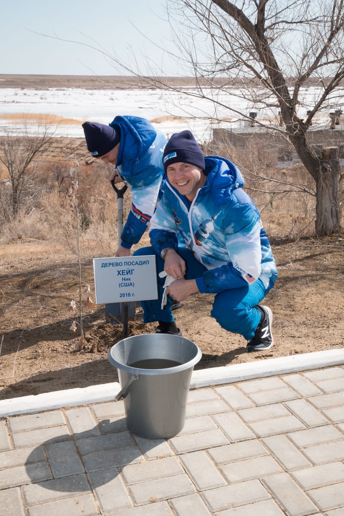 At the Cosmonaut Hotel crew quarters in Baikonur, Kazakhstan, Expedition 59 crew member Nick Hague of NASA poses for pictures March 7 in front of a tree he originally planted last October before his first flight. Preparing the tree for watering is crewmate Alexey Ovchinin of Roscosmos. They launched together last October 11, but their flight was cut short two minutes after launch by an abort triggered by a first-stage booster rocket separation problem. They are set to launch again March 14, U.S. time, this time with crewmate Christina Koch of NASA on the Soyuz MS-12 spacecraft from the Baikonur Cosmodrome for a six-and-a-half month mission on the International Space Station.
