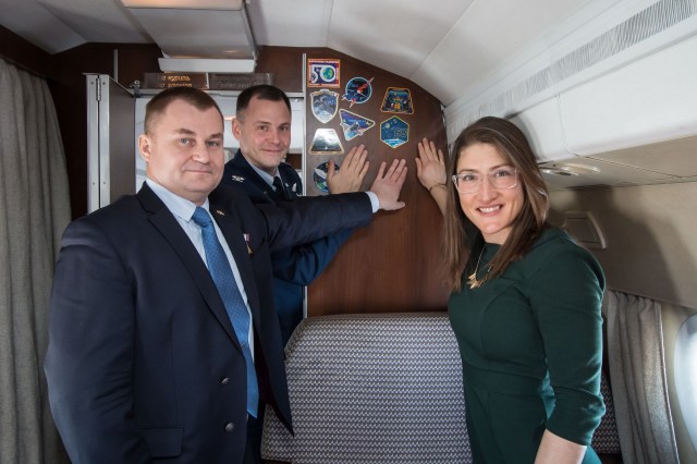 Aboard a Gagarin Cosmonaut Training Center aircraft, Expedition 59 crew members Alexey Ovchinin of Roscosmos (left), Nick Hague of NASA (center) and Christina Koch of NASA (right) display crew insignia stickers on the wall of the cabin Feb. 26 as they flew to their launch site at the Baikonur Cosmodrome in Kazakhstan from Star City, Russia for final pre-launch training. They will launch March 14, U.S. time, on the Soyuz MS-12 spacecraft from the Baikonur Cosmodrome in Kazakhstan for a six-and-a-half month mission on the International Space Station.