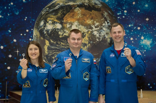 At the Baikonur Cosmodrome Museum in Kazakhstan, Expedition 59 crew members Christina Koch of NASA (left), Alexey Ovchinin of Roscosmos (center) and Nick Hague of NASA (right) display copies of the “launch keys” March 10 during traditional pre-launch activities. An actual key is inserted into a device at the Cosmodrome’s launch control center and rotated into a “start” position to initiate a terminal countdown sequence for a Soyuz rocket prior to liftoff. Koch, Hague and Ovchinin will launch March 14, U.S. time, in the Soyuz MS-12 spacecraft from the Baikonur Cosmodrome for a six-and-a-half month mission on the International Space Station.
