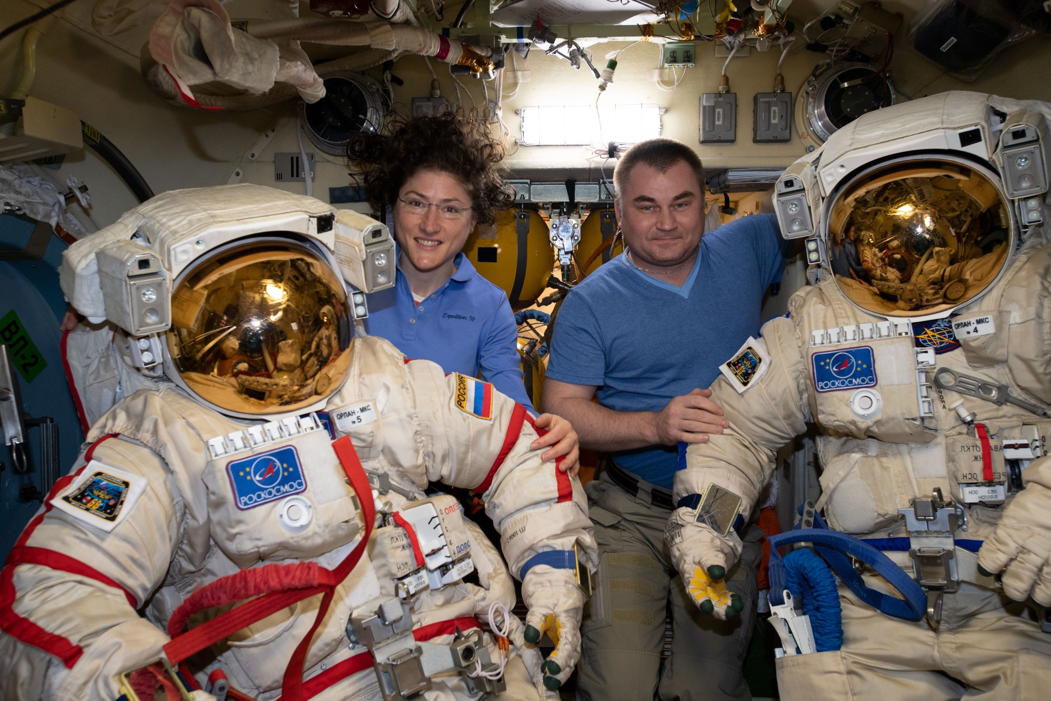 Expedition 59 Flight Engineers Christina Koch of NASA and Alexey Ovchinin of Roscosmos ready a pair of Russian Orlan spacesuits inside the Pirs docking compartment's airlock. Ovchinin and Commander Oleg Kononenko are due to conduct the fourth spacewalk of 2019 for space station maintenance on May 29.