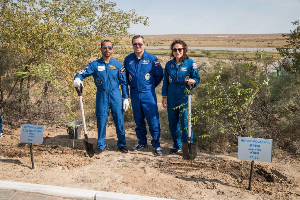 At the Cosmonaut Hotel crew quarters in Baikonur, Kazakhstan, spaceflight participant Hazzaa Ali Almansoori of the United Arab Emirates (left) and Expedition 61 crewmember Jessica Meir of NASA (right) pose for pictures Sept. 18 after planting trees in their names in a traditional pre-launch activity. Joined by Expedition 61 crewmember Oleg Skripochka of Roscosmos (center), they will launch Sept. 25 from the Baikonur Cosmodrome in Kazakhstan on the Soyuz MS-15 spacecraft for a mission on the International Space Station.
