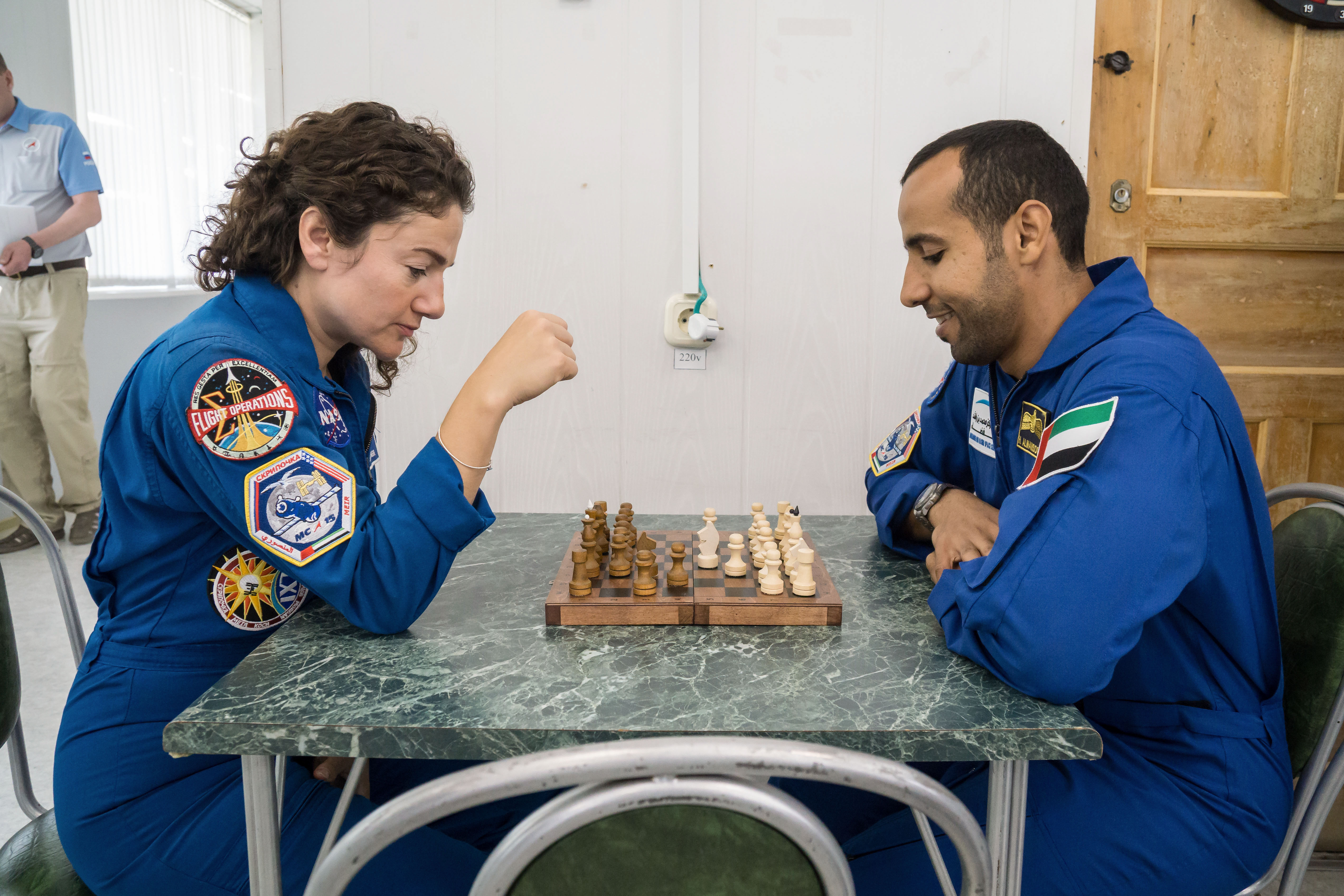 At the Cosmonaut Hotel crew quarters in Baikonur, Kazakhstan, Expedition 61 crewmember Jessica Meir of NASA (left) and spaceflight participant Hazzaa Ali Almansoori of the United Arab Emirates (right) share a game of chess Sept. 18 as part of pre-launch activities. Along with Oleg Skripochka of Roscosmos, they will launch Sept. 25 from the Baikonur Cosmodrome in Kazakhstan on the Soyuz MS-15 spacecraft for a mission on the International Space Station.