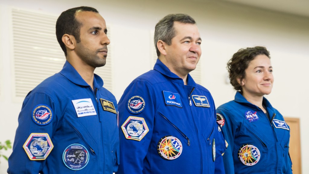 At the Gagarin Cosmonaut Training Center in Star City, Russia, the next crew to launch to the International Space Station reports to Russian, American and United Arab Emirates space officials Aug. 29 during their final qualification exams for flight. From left to right are United Arab Emirates spaceflight participant Hazzaa Ali Almansoori, and Expedition 61 crewmembers Oleg Skripochka of Roscosmos and Jessica Meir of NASA. They will launch Sept. 25 from the Baikonur Cosmodrome in Kazakhstan on the Soyuz MS-15 spacecraft.