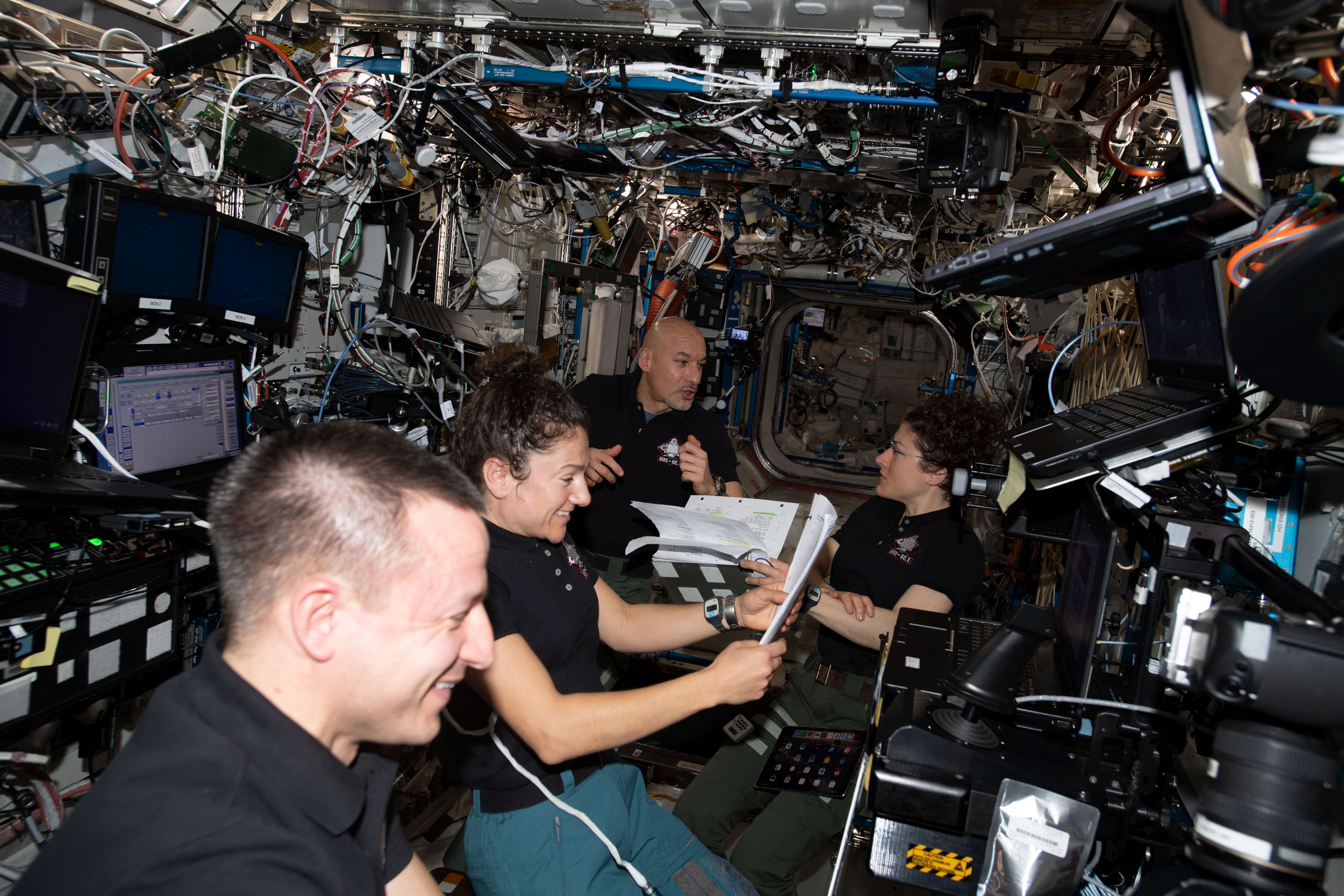 Expedition 61 crewmembers (from left) Andrew Morgan, Jessica Meir, Luca Parmitano and Christina Koch gather inside the U.S. Destiny laboratory module to review spacewalk procedures for the complex repair work planned for the International Space Station's cosmic particle detector, the Alpha Magnetic Spectrometer.