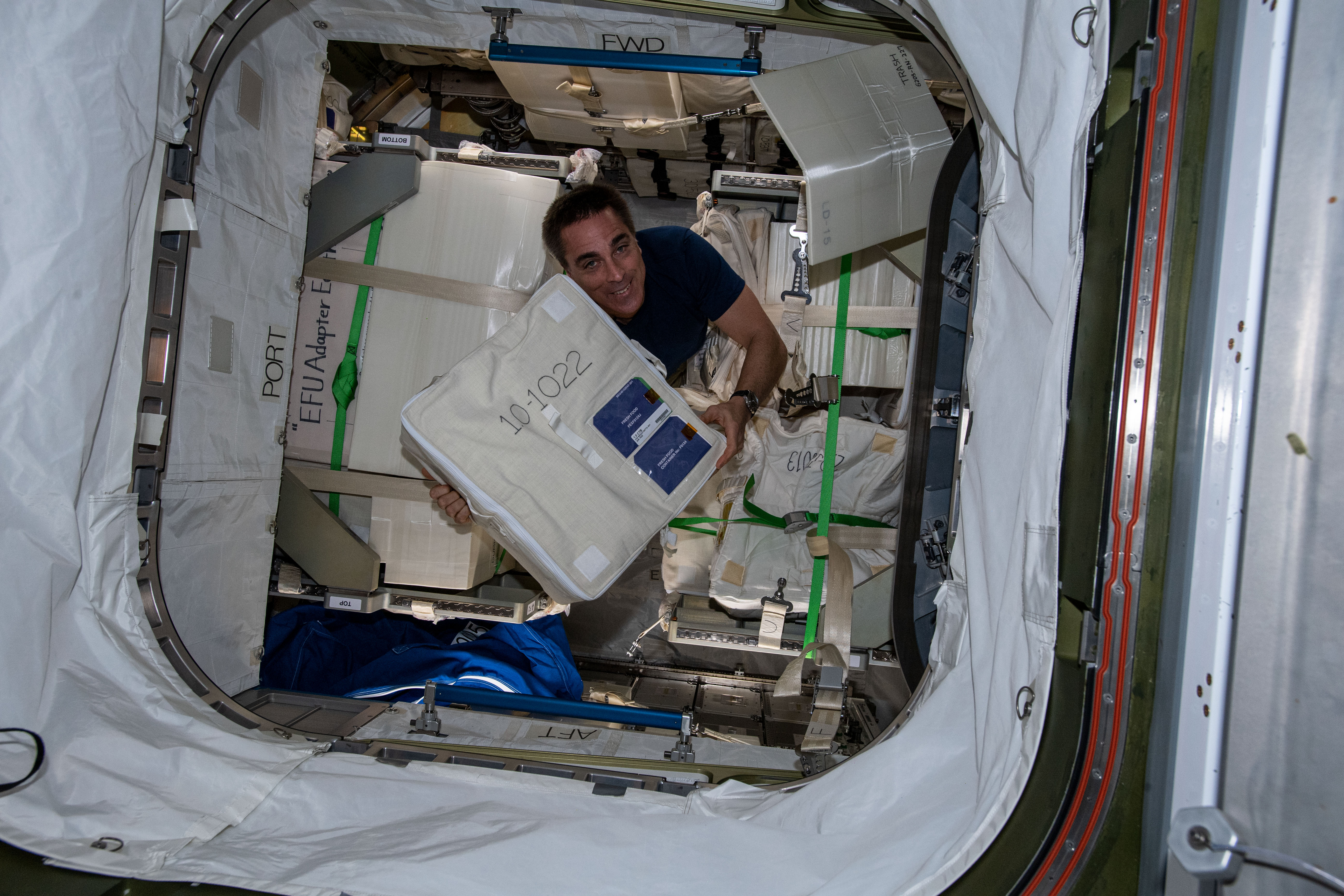 NASA astronaut and Expedition 63 Commander Chris Cassidy unloads a bag packed with fresh food from Japan's resupply ship, the H-II Transfer Vehicle-9 (HTV-9), that had arrived at the International Space Station the day before.