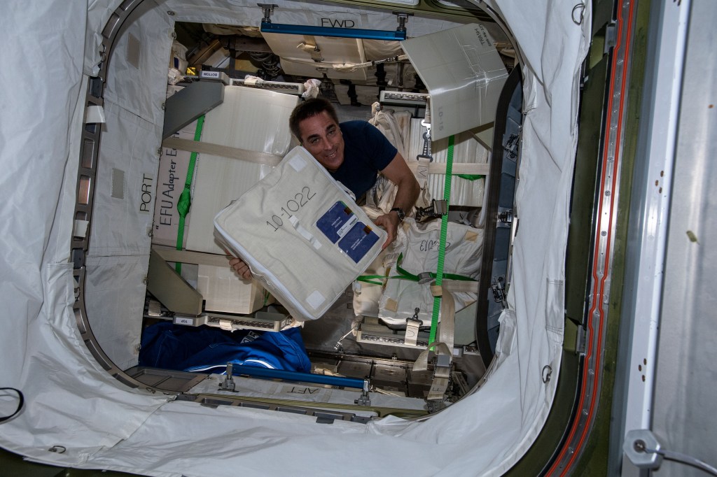 NASA astronaut and Expedition 63 Commander Chris Cassidy unloads a bag packed with fresh food from Japan's resupply ship, the H-II Transfer Vehicle-9 (HTV-9), that had arrived at the International Space Station the day before.