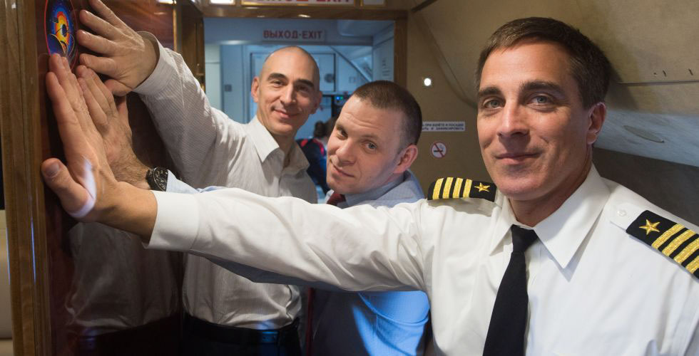 Aboard a Gagarin Cosmonaut Training Center aircraft, Expedition 63 crewmembers Anatoly Ivanishin (left) and Ivan Vagner (center) of Roscosmos and Chris Cassidy (right) of NASA affix a decal of their mission insignia on the wall of their plane March 24 as they flew to their launch site at the Baikonur Cosmodrome in Kazakhstan. They will launch April 9 on the Soyuz MS-16 spacecraft from Baikonur for a six-and-a-half month mission on the International Space Station.