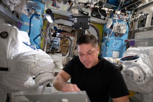 NASA astronaut and Expedition 63 Flight Engineer Bob Behnken reviews maintenance procedures on a computer while working on U.S. spacesuits inside the International Space Station's Quest airlock.