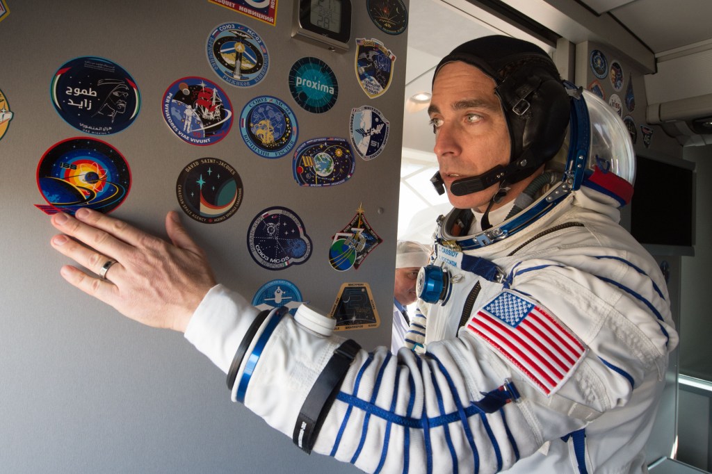 Expedition 63 crewmember Chris Cassidy of NASA applies a mission sticker to the interior of the crew bus as he, Anatoly Ivanishin, and Ivan Vagner of Roscosmos arrive at the launch pad, Thursday, April 9, 2020 at the Baikonur Cosmodrome in Kazakhstan. A few hours later, they lifted off on a Soyuz rocket for a six-and-a-half month mission on the International Space Station.