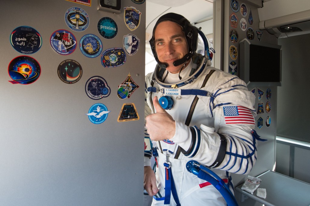 Expedition 63 crewmember Chris Cassidy of NASA gives a thumbs up onboard the crew bus as he, Anatoly Ivanishin, and Ivan Vagner of Roscosmos arrive at the launch pad, Thursday, April 9, 2020 at the Baikonur Cosmodrome in Kazakhstan. A few hours later, they lifted off on a Soyuz rocket for a six-and-a-half month mission on the International Space Station.