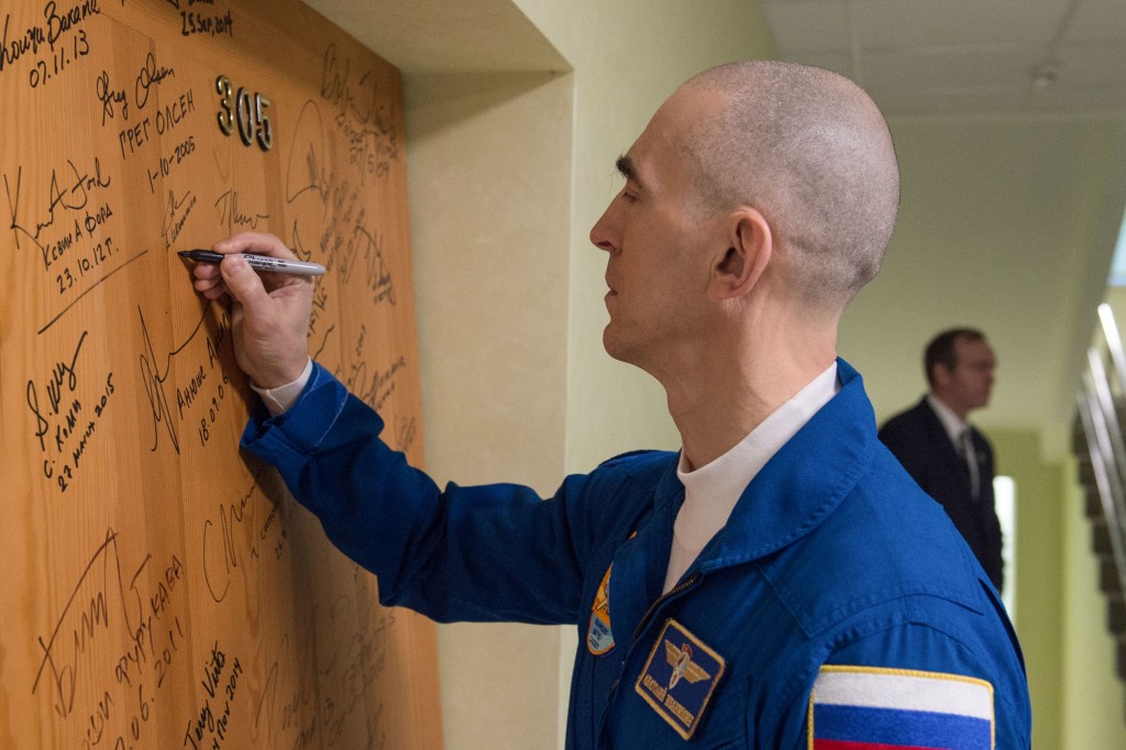 Expedition 63 crewmember Anatoly Ivanishin of Roscosmos signs a door in the Cosmonaut Hotel prior to departing for launch on a Soyuz rocket with Chris Cassidy of NASA, and Ivan Vagner of Roscosmos, Thursday, April 9, 2020 in Baikonur, Kazakhstan. The crew is beginning a six-and-a-half month mission on the International Space Station.