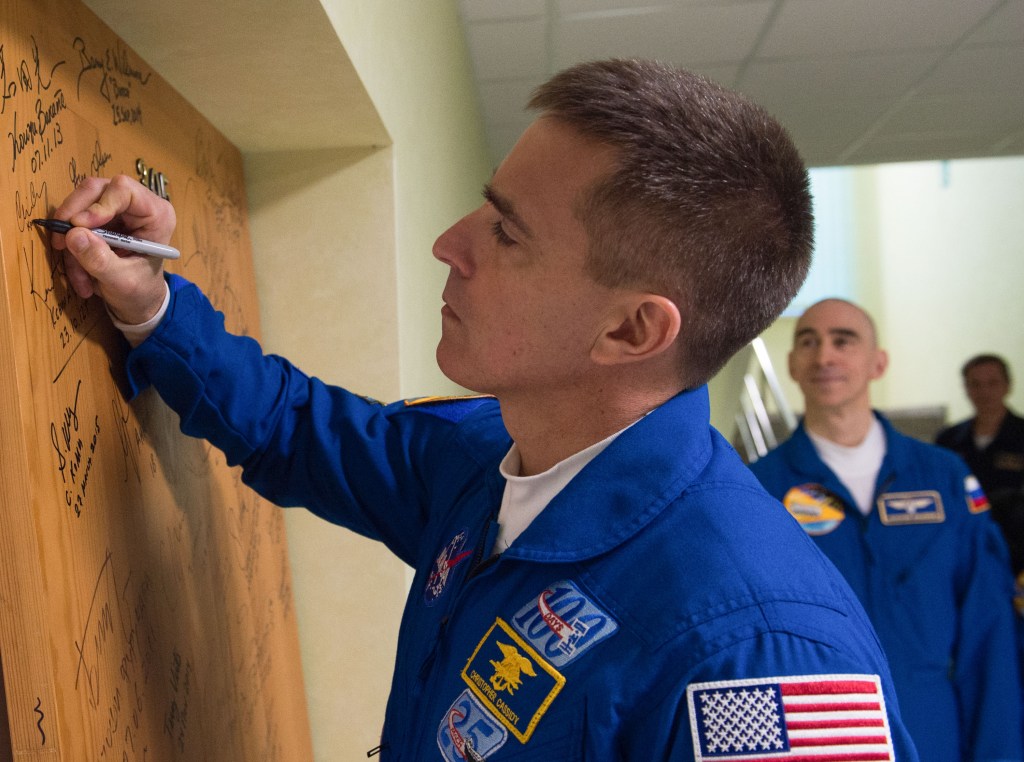 Expedition 63 crewmember Chris Cassidy of NASA signs a door in the Cosmonaut Hotel prior to departing for launch on a Soyuz rocket with Anatoly Ivanishin and Ivan Vagner of Roscosmos, Thursday, April 9, 2020 in Baikonur, Kazakhstan. The crew is beginning a six-and-a-half month mission on the International Space Station.