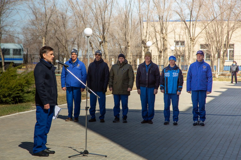 At the Cosmonaut Hotel crew quarters in Baikonur, Kazakhstan, cosmonaut Yuri Malenchenko (left), who is the Deputy Director of the Gagarin Cosmonaut Training Center, presides over the traditional flag-raising ceremony March 26 as part of pre-launch activities for the Expedition 63 crew. The prime and backup crews are seen from left to right --- prime crewmembers Chris Cassidy of NASA, Anatoly Ivanishin and Ivan Vagner of Roscosmos and the backup crewmembers, Steve Bowen of NASA and Sergey Ryzhikov and Andrei Babkin of Roscosmos. Cassidy, Ivanishin and Vagner will launch April 9 from the Baikonur Cosmodrome on the Soyuz MS-16 spacecraft for a six-and-a-half month mission on the International Space Station.
