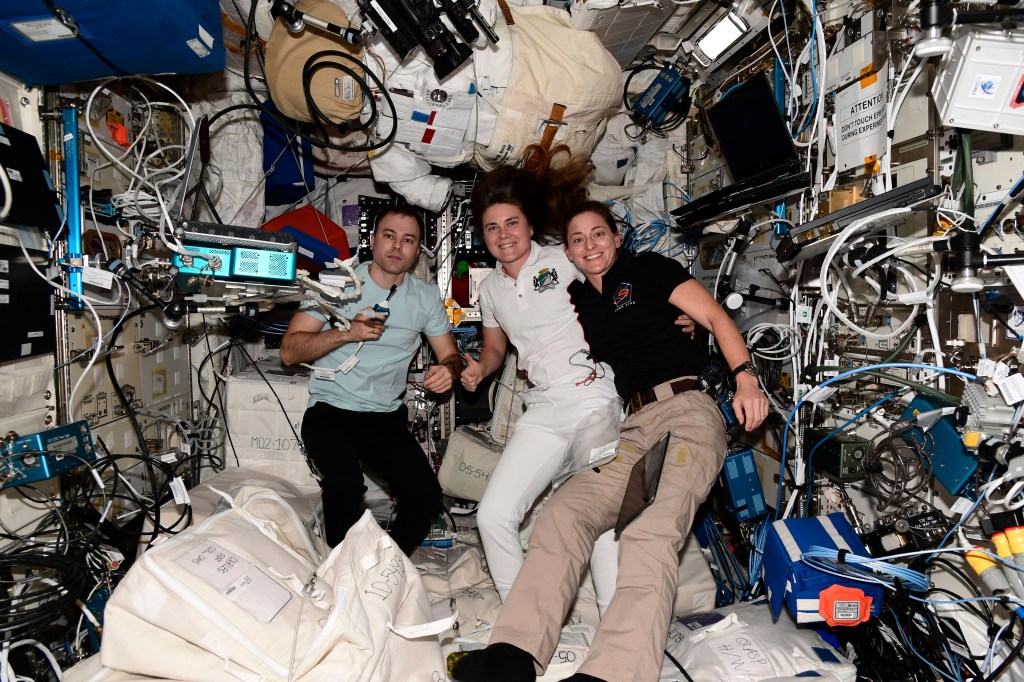 iss068e042985 (Jan. 26, 2023) --- (From left) Expedition 68 Flight Engineers Dmitri Petelin and Anna Kikina, both from Roscosmos, and Nicole Mann from NASA pose for a portrait inside the International Space Station's Columbus laboratory module. Credit: Roscosmos