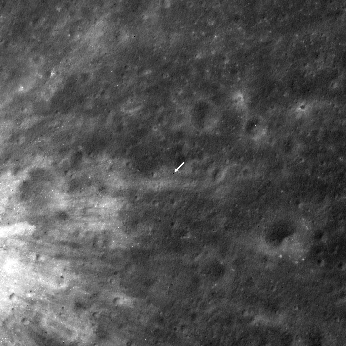 A black and white image of the surface of the moon taken from NASA's LRO showing a white dot that is JAXA's SLIM lander.