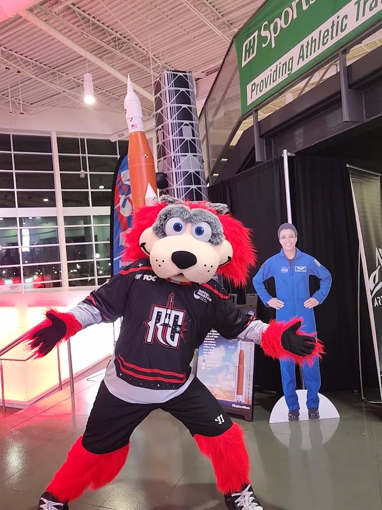 Huntsville Havoc mascot, Rukus, poses in front of NASA exhibits at Space Night.