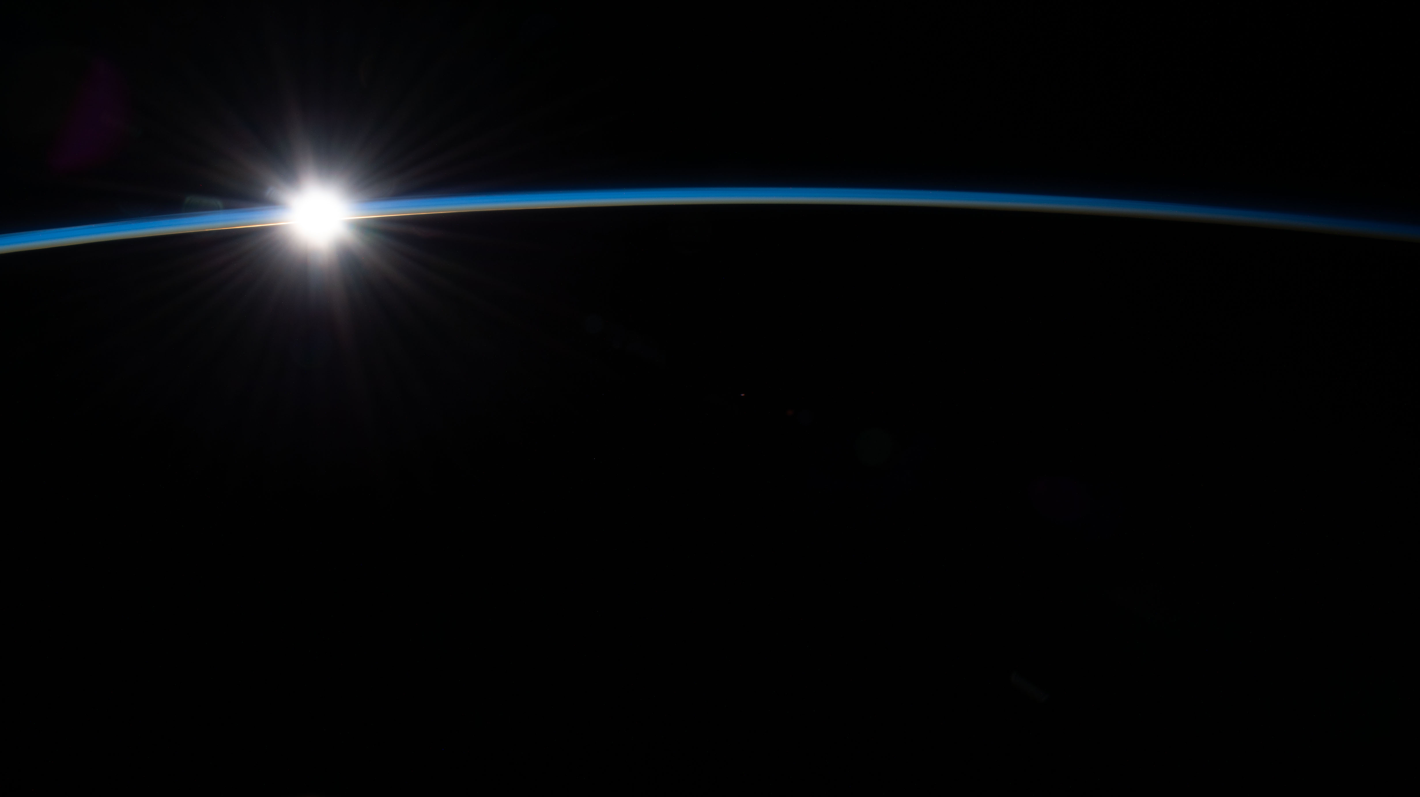 The first rays of an orbital sunrise penetrate Earth's atmosphere in this photograph from the International Space Station as it orbited 263 miles above the Atlantic Ocean off the coast of the Canadian island of Newfoundland.