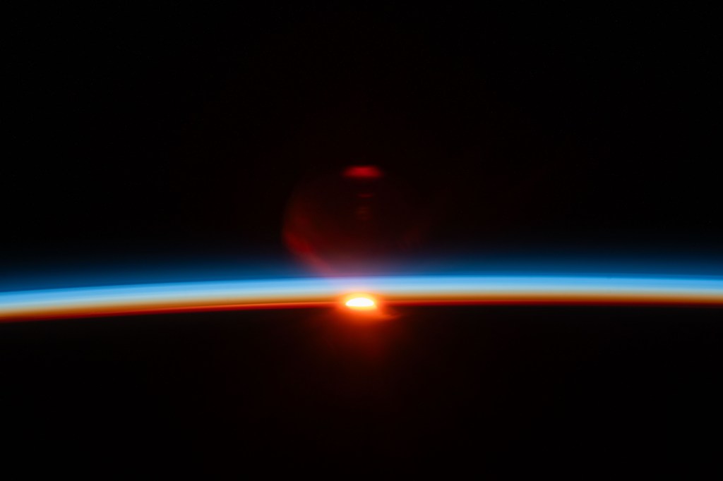The sun's last rays illuminate Earth's atmosphere and refract in the camera lense in this photograph of an orbital sunset from the International Space Station as it soared 261 miles above the Pacific Ocean off the northern coast of Japan.
