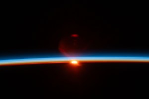 The sun's last rays illuminate Earth's atmosphere and refract in the camera lense in this photograph of an orbital sunset from the International Space Station as it soared 261 miles above the Pacific Ocean off the northern coast of Japan.