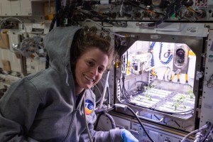 NASA astronaut and Expedition 70 Flight Engineer Loral O'Hara poses in front of the Kibo laboratory module's Advanced Plant Habitat housing tomato plants for an experiment investigating how the plant immune system adapts to spaceflight and how spaceflight affects plant production.