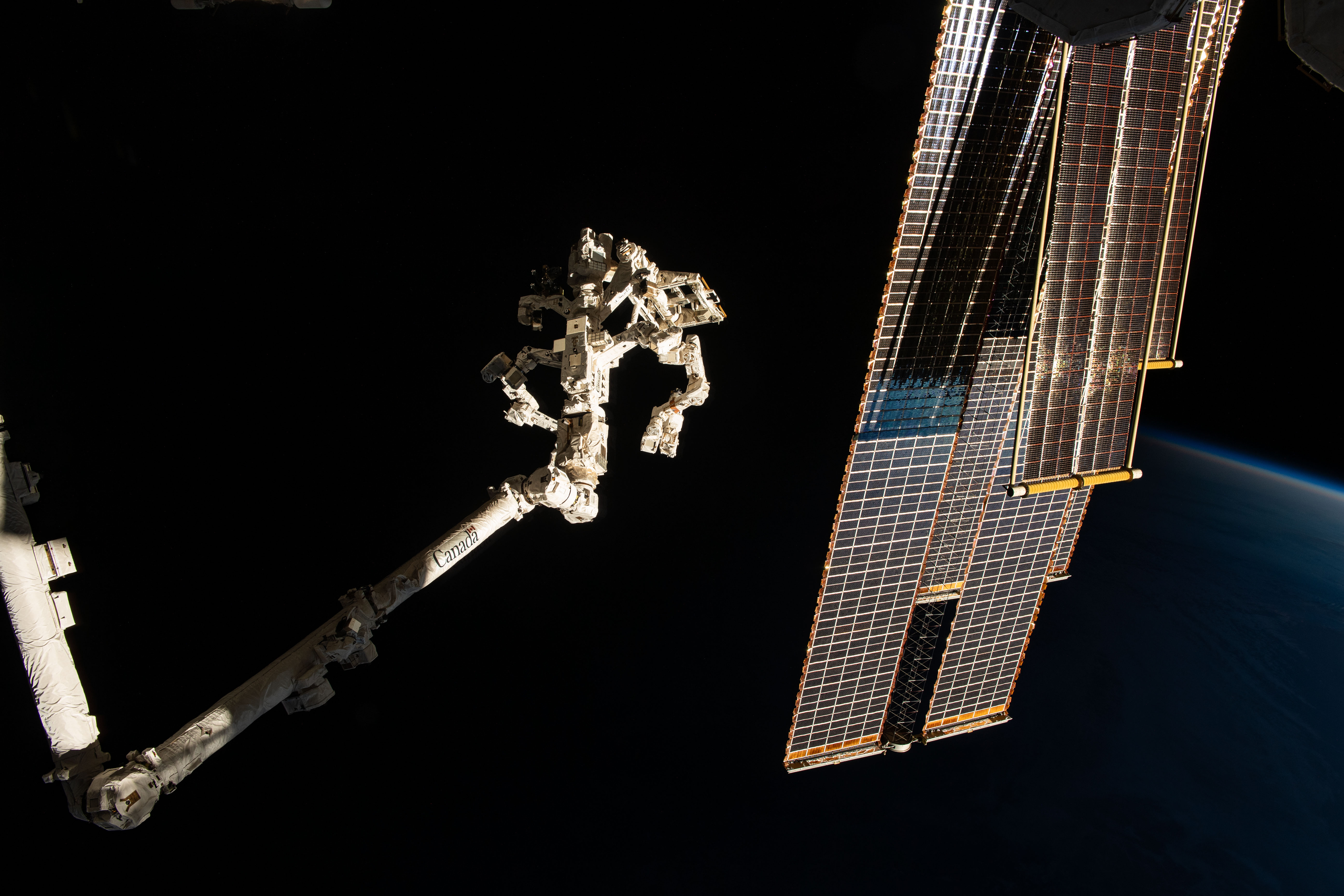 The Earth's horizon is barely visible as the International Space Station soars into an orbital sunset 261 miles above northeastern China. In the foreground, are the Canadarm2 robotic arm (left) with the Dextre fine-tuned robotic hand attached and the orbital outpost's main solar arrays (right) and shorter roll-out solar arrays.