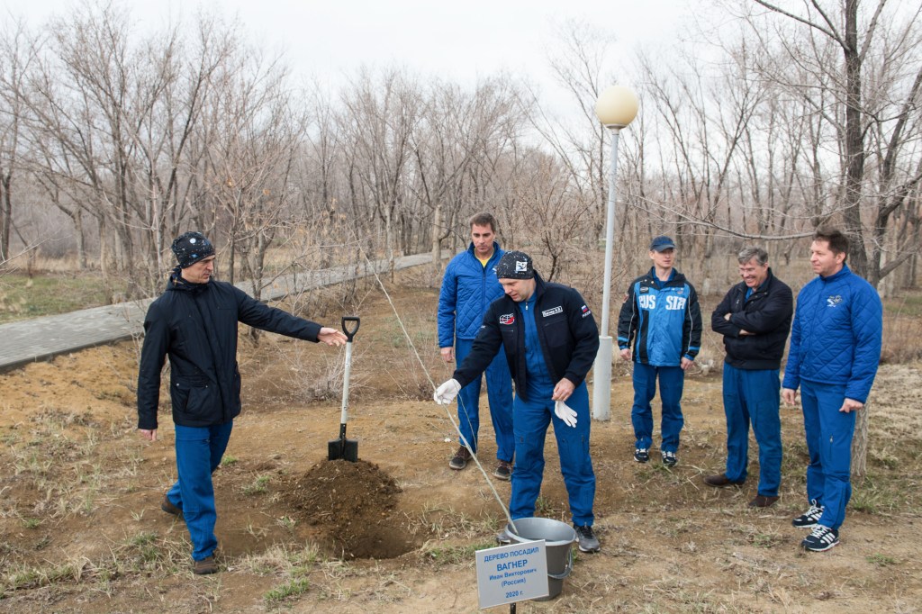 At the Cosmonaut Hotel crew quarters in Baikonur, Kazakhstan, Expedition 63 crewmember Ivan Vagner of Roscosmos (center) plants a tree bearing his name April 1 in traditional pre-launch activities. Looking on are crewmates Anatoly Ivanishin of Roscosmos (left) and Chris Cassidy of NASA (second from left) and backup crewmembers Sergey Ryzhikov of Roscosmos, Steve Bowen of NASA and Andrei Babkin of Roscosmos on the right. Cassidy, Ivanishin and Vagner will launch April 9 on the Soyuz MS-16 spacecraft from the Baikonur Cosmodrome in Kazakhstan for a six-and-a-half month mission on the International Space Station. Credit: Andrey Shelepin/Gagarin Cosmonaut Training Center.