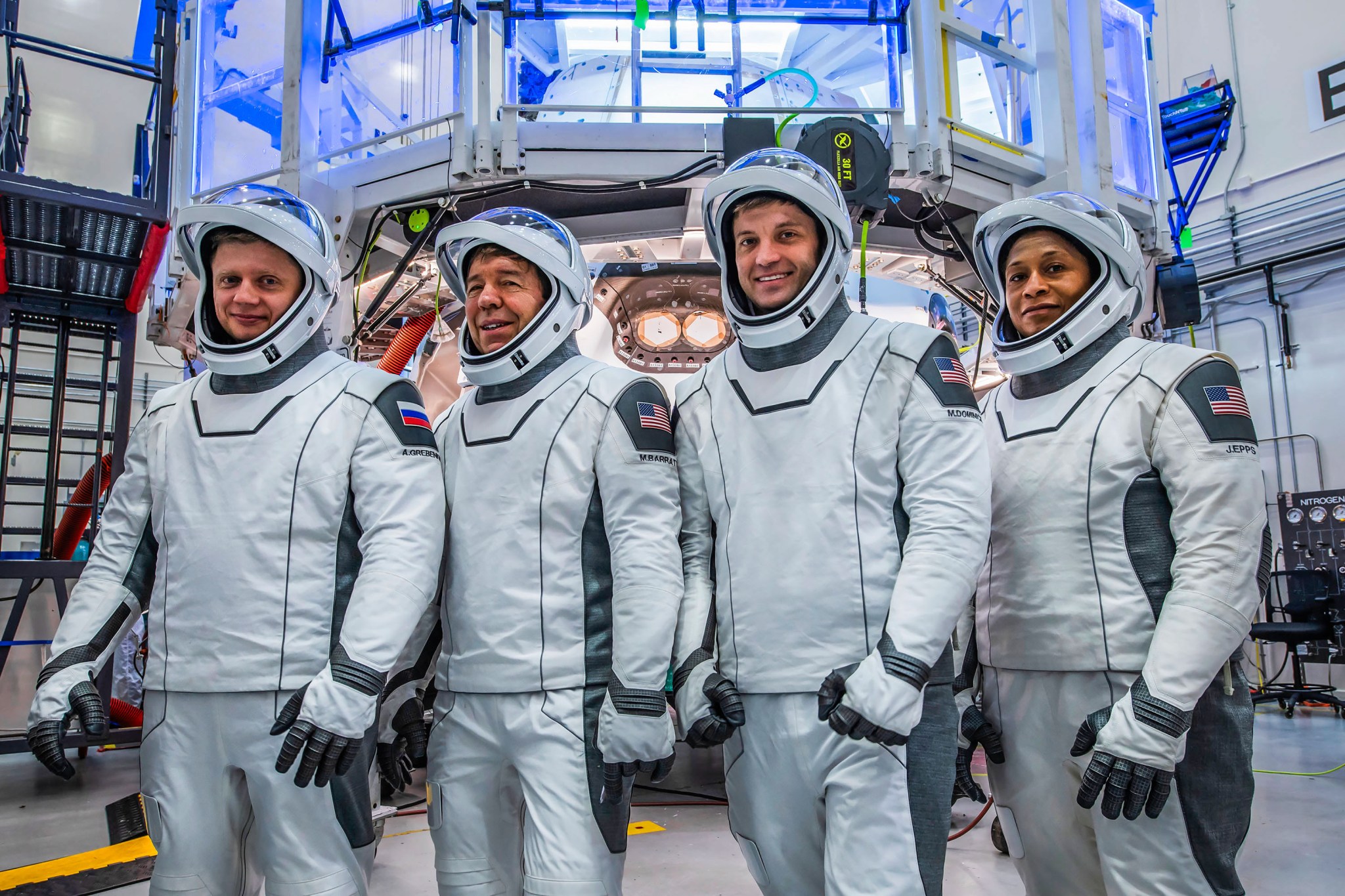 (Left to right) Roscosmos Cosmonaut Alexander Grebenkin and NASA Astronauts Michael Barratt, Matthew Dominick, and Jeanette Epps pose for a photo during their Crew Equipment Interface Test at NASA’sa Kennedy Space Center in Florida. The goal of the training is to rehearse launch day activities and get a close look at the spacecraft that will take them to the International Space Station.