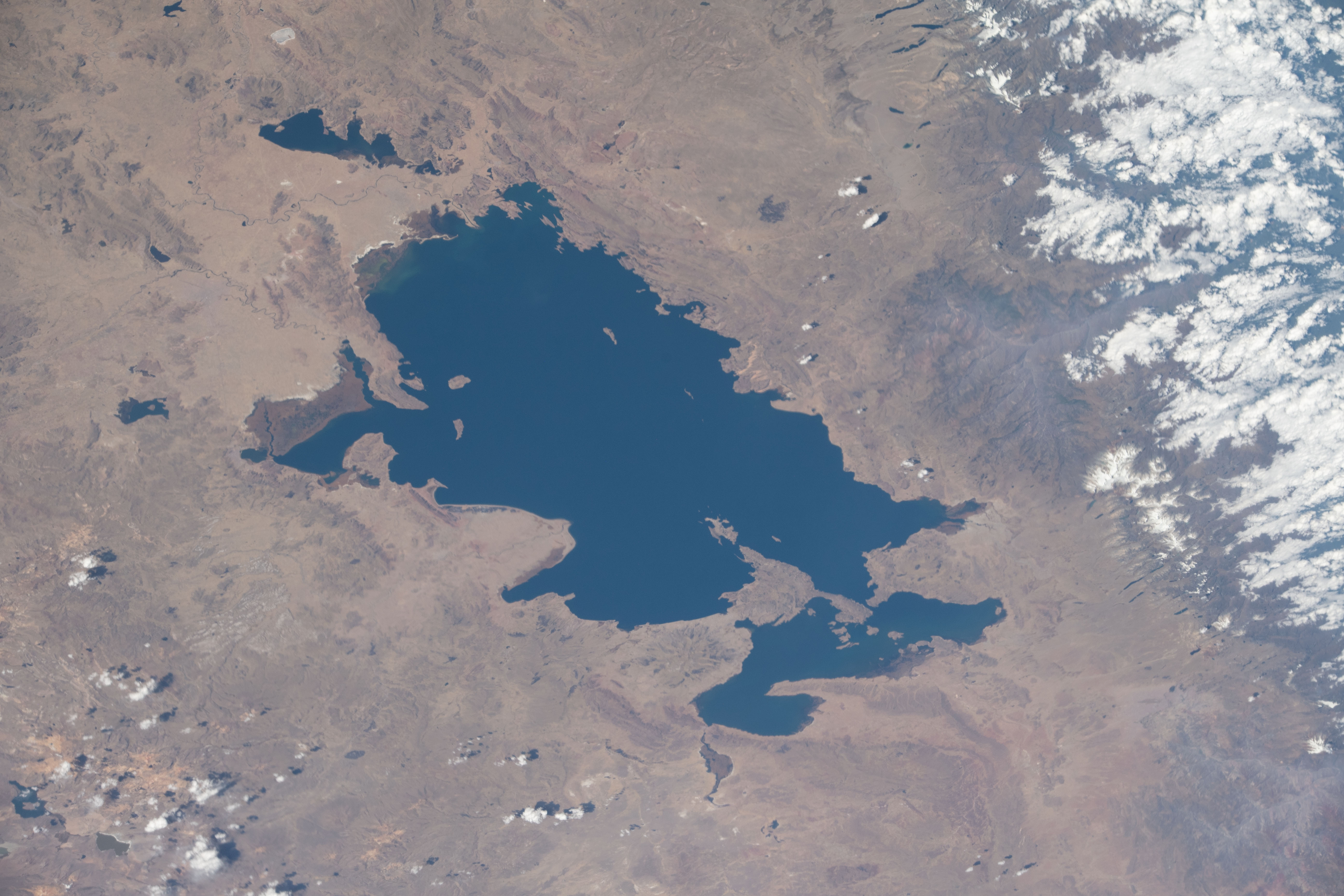 Lake Titicaca, pictured from the International Space Station as it orbited off the Pacific coast of South America, is located between the nations of Peru and Bolivia in the Andes Mountains and is one of the highest navigable lakes in the world.