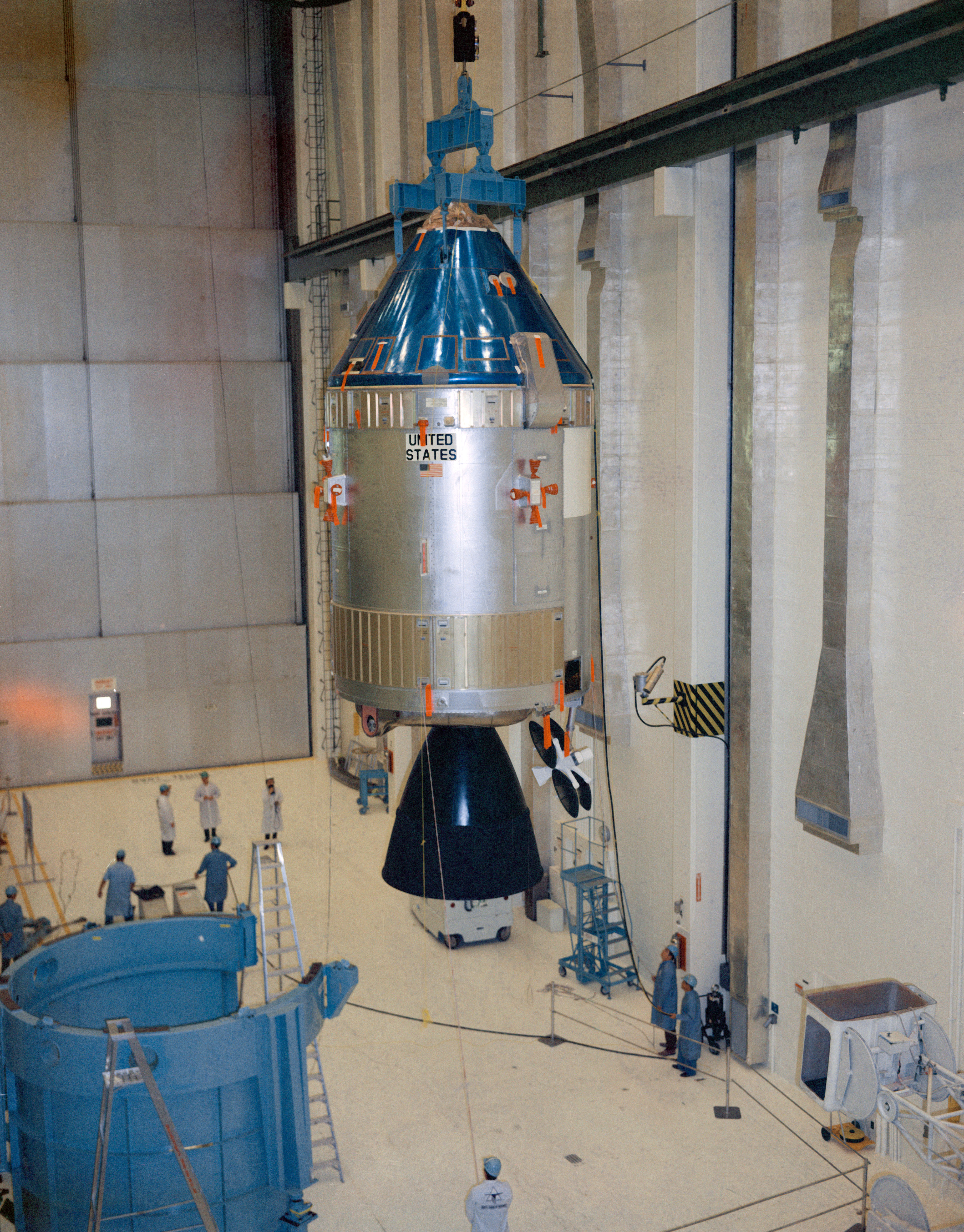 After installing the main engine bell, workers lift the Command and Service Module for mating with the SLA