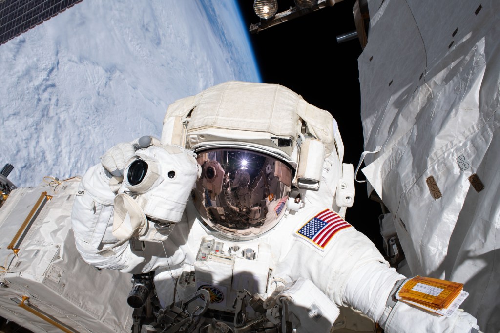 NASA astronaut and spacewalker Andrew Morgan prepares to take a photograph with a camera protected from the hazards of microgravity by shielding. He and fellow astronaut Luca Parmitano (out of frame) were conducting the second spacewalk to repair the International Space Station's cosmic particle detector, the Alpha Magnetic Spectrometer.
