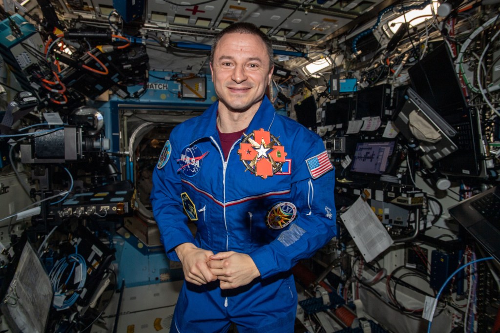 NASA astronaut Andrew Morgan, who is also a medical doctor in the U.S. Army, displays his Brooke Army Medical Center Commander’s Coin aboard the International Space Station.
