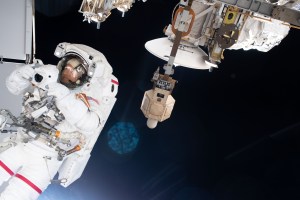 NASA astronaut Andrew Morgan takes pictures with a camera shielded from the effects of microgravity during a spacewalk to finalize thermal repairs on the Alpha Magnetic Spectrometer, a dark matter and antimatter detector.