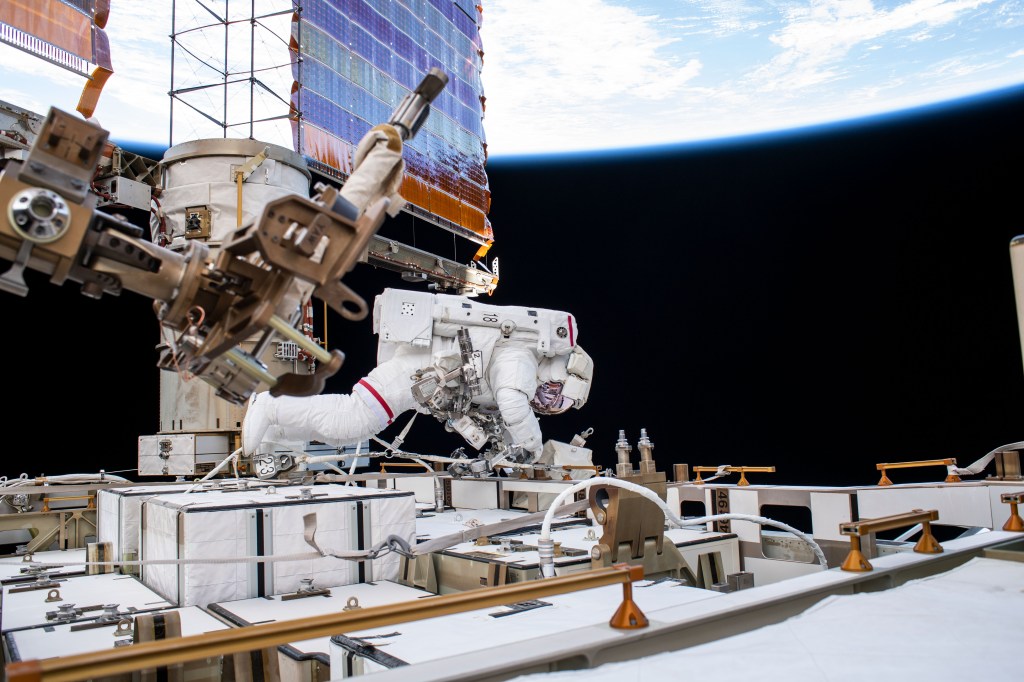 NASA astronaut Andrew Morgan works while tethered on the Port 6 truss segment of the International Space Station to replace older hydrogen-nickel batteries with newer, more powerful lithium-ion batteries. The batteries store and distribute power collected from the station's basketball court-sized solar arrays, one of which is directly behind Morgan.