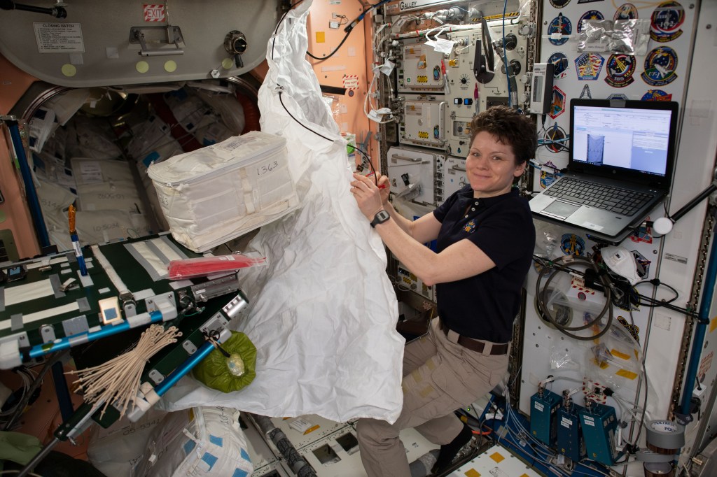 NASA astronaut Anne McClain assembles a hygiene cover that will cover a rack bay inside the Permanent Multipurpose Module.