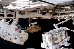 NASA astronaut Bob Behnken (at left) is pictured during a spacewalk to swap batteries and upgrade power systems on the International Space Station's Starboard-6 truss structure. Pictured at lower right, is an external pallet, gripped by the Canadarm2 robotic arm, that housed the batteries replaced on the orbiting lab. Behnken was joined during the six-hour and seven-minute excursion by NASA astronaut Chris Cassidy (out of frame).