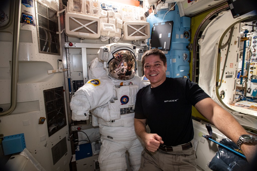 Expedition 63 Flight Engineer and NASA astronaut Bob Behnken poses with a U.S. spacesuit inside the International Space Station's Quest airlock.