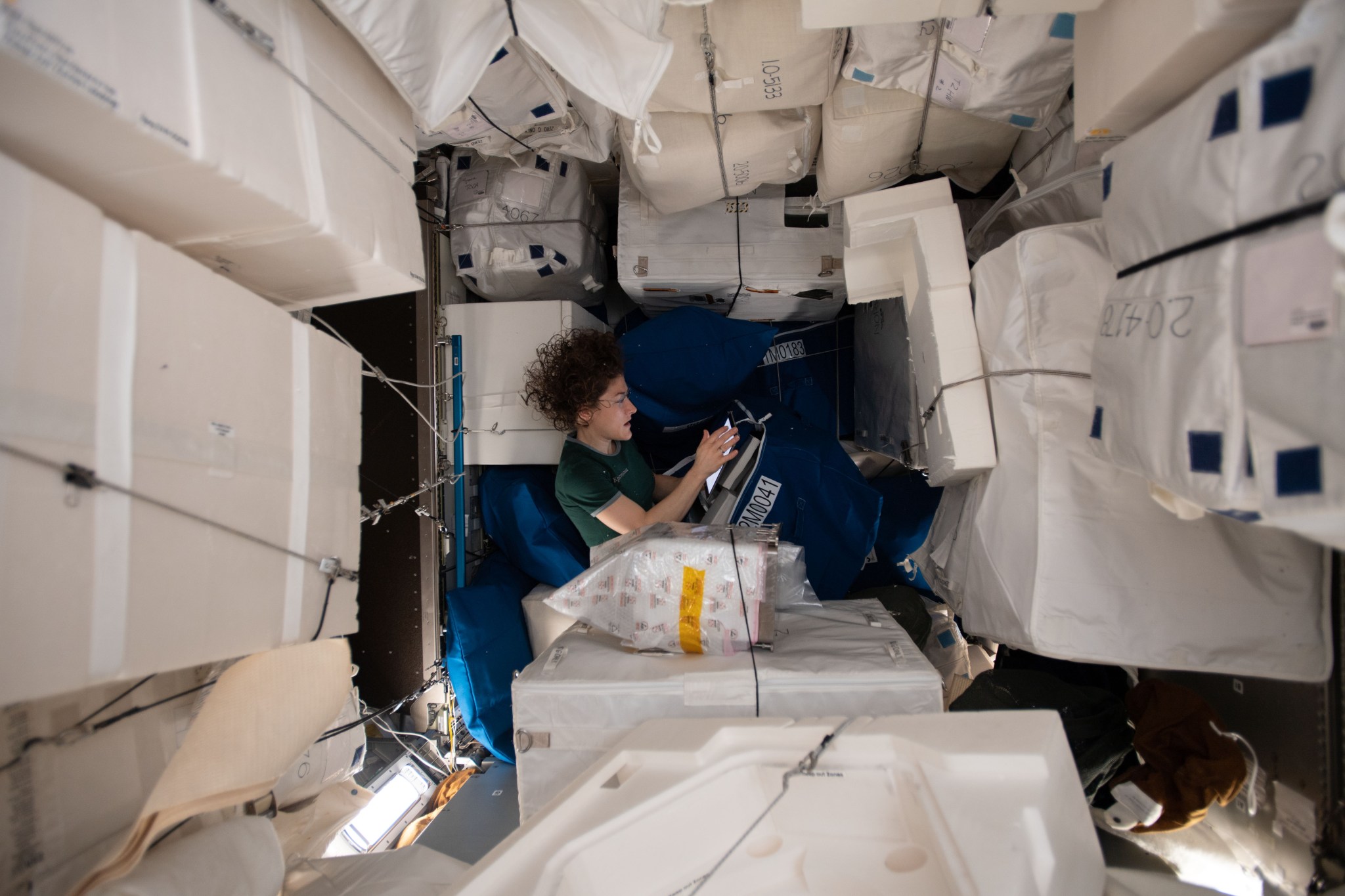 NASA astronaut Christina Koch relocates and organizes International Space Station hardware inside the Leonardo Permanent Multipurpose Module (PMM) from ESA (European Space Agency). The PMM is attached to the forward-facing facing portion of the Tranquility module. Directly opposite of the PMM on Tranquility is the Bigelow Expandable Activity Module (BEAM).