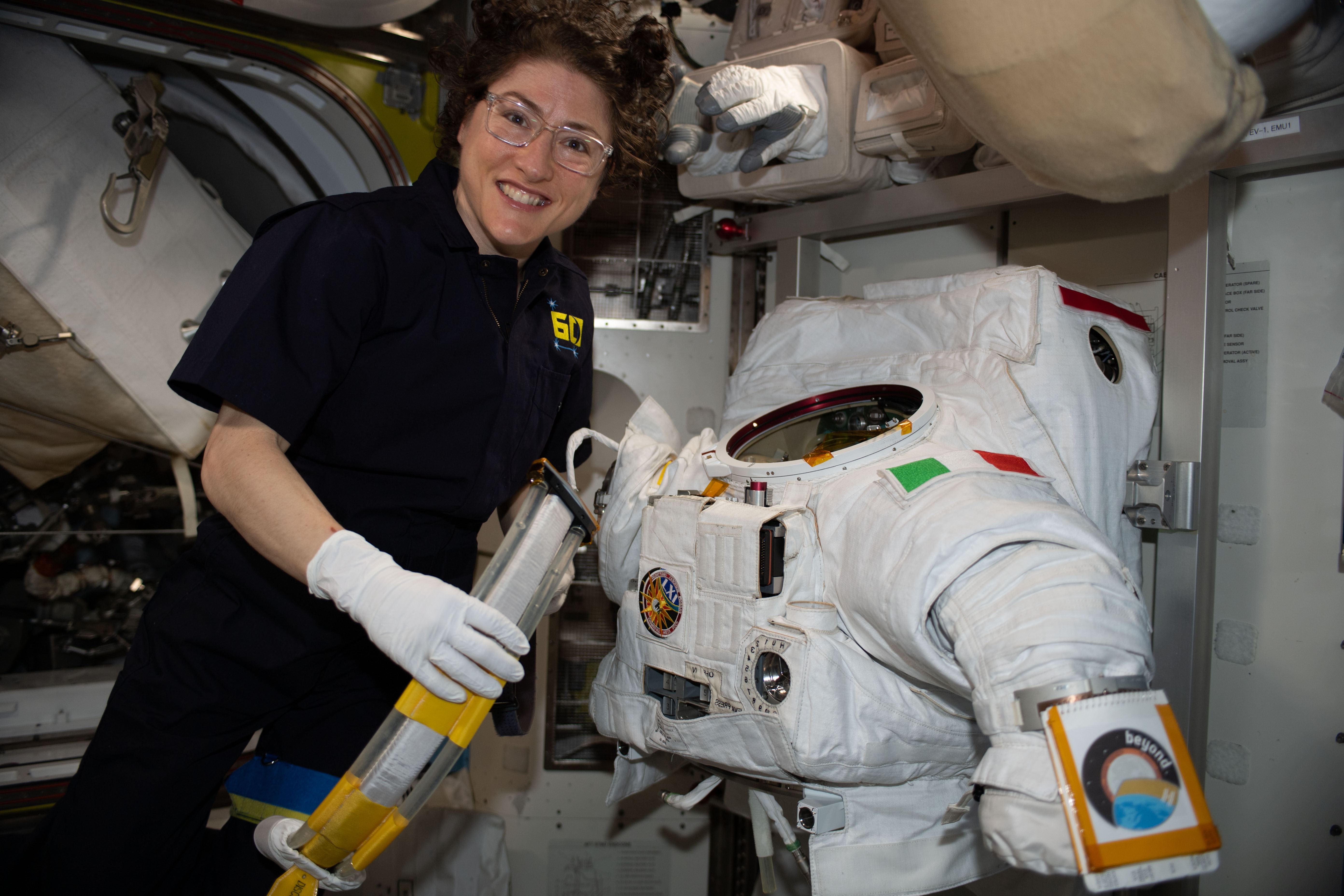 NASA astronaut Christina Koch works on a U.S. spacesuit, with a patch of the Italian flag on the left shoulder, that Commander Luca Parmitano of ESA (European Space Agency) wore during a spacewalk on Dec. 2, 2019.